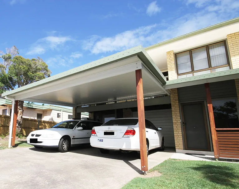 Carport and covered outdoor area built off the side of a brick home